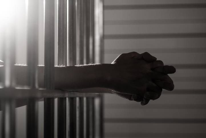 Close up of hands and prison yard bars